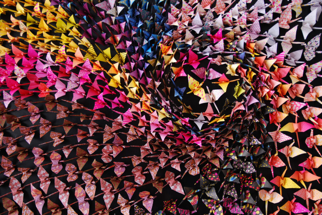 Close-up of origami art, 1000 folded cranes arranged in a swirl